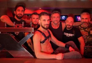 Group of gay men at a Paris gay cruise club. Man in leather harness. Nightlife scene. Gay travel advice.