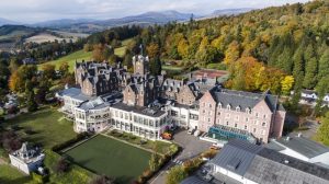 Aerial view of Crieff Hydro, a gay-friendly hotel in Scotland. Resort with mountains, trees, & green lawns. Ideal for gay travel.