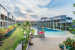 Avani+ Hua Hin Resort view. Gay-friendly hotel with pool, palm trees, sun loungers, and modern architecture. Ideal for gay travel and relaxation.