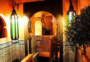 Le Riad Paris interior. Ornate Moroccan design with lamps, tiles, and a circular archway. Gay travel advice for a stylish stay in Paris.