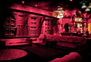 Star City, Paris: Interior view of the gay bar bathed in red light, featuring ornate wooden decor, cozy seating, and unique lighting fixtures.