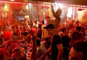 The LABO Paris Gay Bar: Crowded scene with a drag queen performer. Gay men enjoy the vibrant atmosphere. Paris nightlife.