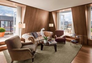 The London EDITION hotel suite. Luxury gay hotel in Soho, London. Living room with sofa, chairs, and balcony access. Coolest hotel.