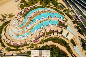 Aerial view of W Dubai - The Palm, a gay-friendly hotel. Pools, beach chairs, and architecture create a luxurious resort experience.