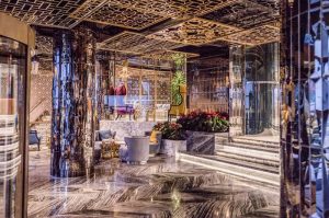 Elysium Taksim Hotel's luxurious lobby. This gay-friendly hotel features marble floors, mirrored pillars, and ornate gold ceiling designs.