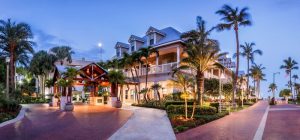 Opal Key Resort and Marina, a gay-friendly hotel. Exterior view of the resort at dusk with palm trees and well-lit walkways.