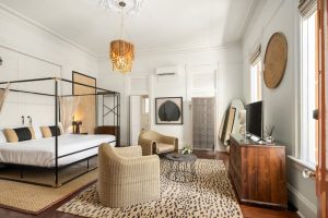 Marrero's Guest Mansion gay-friendly hotel room. Canopy bed, rattan chairs, and animal print rug. Stylish gay travel lodging.