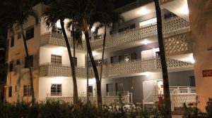 Hotel Gaythering, a gay-friendly hotel welcoming adults. Night view of the hotel's exterior with palm trees. Miami Beach gay travel.