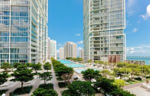 W Miami gay-friendly hotel view. Tall buildings, pools, and trees under a blue sky. A great place for gay men to travel and enjoy.