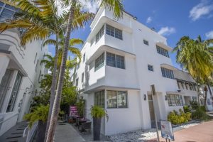 Posh South Beach gay-friendly hotel exterior. White art deco building with palm trees. A stylish choice for gay travelers in South Beach.