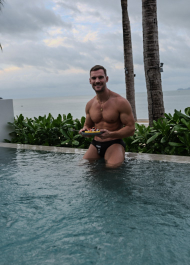 Gay travel Thailand: Steven at Explorar Koh Samui, one of Steven and Manu's top 5 hotels. Muscular man in pool with fruit. Tropical vacation.