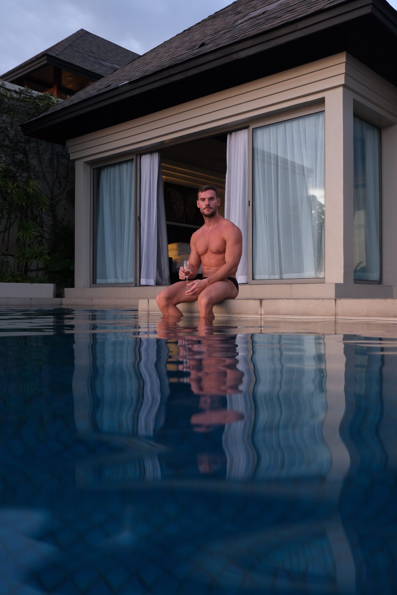 Gay travel: Muscular man at The Pavilions Phuket resort, Thailand. Steven enjoys a drink by the pool in this luxury villa.