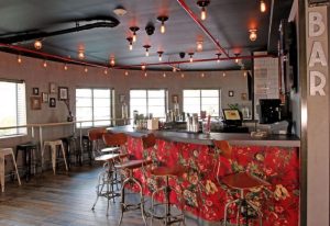 Hotel Gaythering's bar interior. The Gaythering bar features a floral-patterned counter, stools, and unique lighting. Gay travel advice.