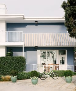 Facade of Bayside Hotel, a gay-friendly hotel. A bicycle stands outside the entrance with a striped awning. Ideal for gay travel.