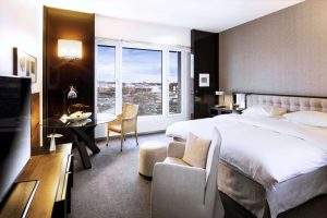 Grand Hyatt Berlin gay-friendly hotel room. Modern design with a bed, chairs, and a view of the city. Luxury travel for gay men in Berlin.