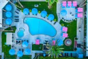 Aerial view of INNdulge, an iconic gay men's resort. Pool, umbrellas, lounge chairs, & cabanas create a relaxing, gay-friendly hotel vibe.