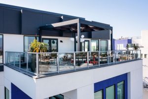 The Shay, a Destination by Hyatt hotel. Modern gay-friendly hotel balcony with glass railings, pergola, and city views. Stylish travel for gay men.