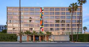 Viceroy Santa Monica, a gay-friendly hotel. Exterior view of the hotel with palm trees and a colorful mural. Gay travel destination.