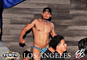 Club Tempo dancer in Los Angeles. Shirtless man with tattoos and cap, wearing a speedo, performs at the gay club. Nightlife scene.
