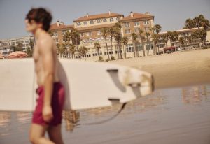 Gay Los Angeles travel: Man with surfboard on Santa Monica Beach. Popular gay travel advice for things to do in LA.
