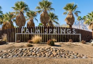 Palm Springs sign with palm trees. Gay Palm Springs travel guide for gay men's travel advice this year.