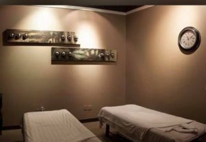 Prince Men's Spa massage room. Two massage tables with white linens, wall art, and a clock. Gay men's travel advice for relaxation.