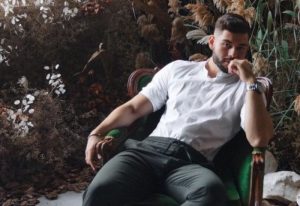 Sasha Bloom by Sasha: Handsome gay man relaxing in a chair. Massage therapist for gay men travel advice. Portrait.