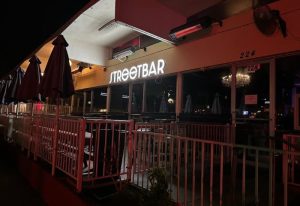 Streetbar front view at night. Outdoor seating area with umbrellas. Gay bar, popular spot for gay men travel.