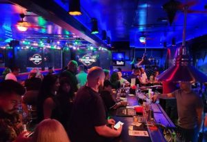 Interior of The Boulevard Bar, a gay bar. Patrons at the bar, with blue lighting and a lively atmosphere. Gay travel destination.