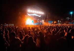Crowd at As One in the Park Festival. Stage lights illuminate the night. A popular gay event for men's travel and music lovers.