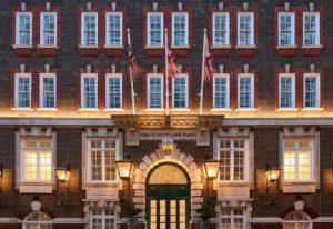 Great Scotland Yard Hotel facade, a luxury gay hotel in London. Union Jack flags fly above the entrance. Best hotel near Soho.