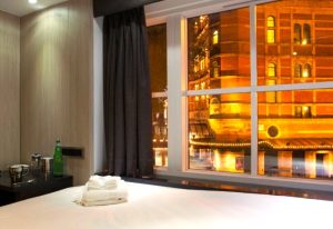 The Z Hotel Soho, London. Hotel room view at night. Most-booked gay hotel near gay bars. Interior with bed, towels, and city lights.