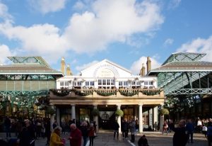Covent Garden Market, near The Z Hotel, a popular gay hotel in London. Tourists gather in the plaza under a partly cloudy sky.