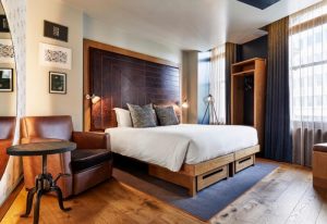 The Hoxton, Holborn hotel room. Coolest gay hotel in London with a leather headboard, chair, and wood floors. Gay travel advice.