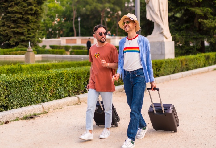 Gay couple with travel equipment. Secure storage options for travel gear. Men with suitcases in park, gay travel tips.