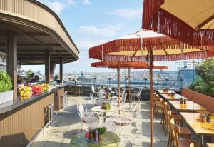 Rooftop bar at Hotel Motto, best boutique gay hotel in Vienna city center. Tables with umbrellas, city view, bar with fruit. Gay travel advice.