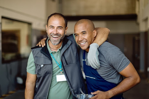 Two smiling men, possibly gay, after a hair transplant in Turkey. Happy with results, gay-friendly options. Cost-effective solution.