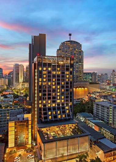 DoubleTree by Hilton Sukhumvit Bangkok, a gay-friendly hotel. Aerial view of the hotel's exterior at dusk, showcasing its modern architecture.