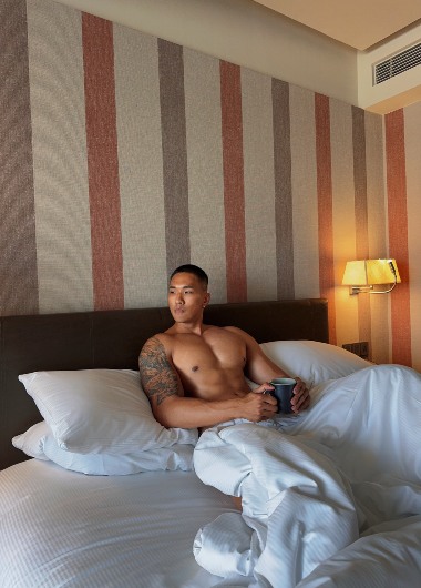 Shirtless man in bed at DoubleTree by Hilton Sukhumvit Bangkok. Thailand hotel room. Gay travel advice. Andee in Bangkok.