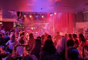 Gay party at Bar Le Cocktail in Montreal. Crowd enjoys a performance under vibrant lighting. Nightlife scene for gay men travel.
