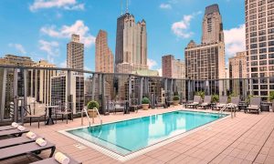 Rooftop pool at a best gay hotel in Chicago. City skyline view with skyscrapers. Loungers and tables surround the pool. Travel advice.