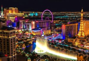Night view of Las Vegas Strip for a Gay Las Vegas Travel Guide. Features the High Roller, Eiffel Tower, and Bellagio fountains.