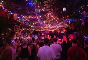 Bovine Sex Club in Toronto: A vibrant, crowded gay club with a live band on stage under a canopy of colorful lights and decorations.
