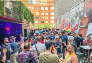 Crowded outdoor patio at Boxers NYC, a popular gay bar. Men gather, drink, and socialize in this vibrant New York City travel destination.