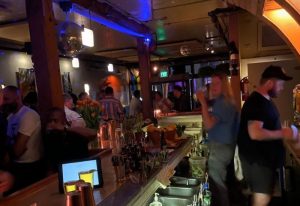 Inside Driftwood Bar in San Francisco. Gay bar scene with disco balls, patrons, and bartenders. Popular gay travel destination.