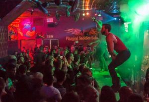 Flaming Saddles Saloon, a gay bar in New York City. Crowd watching male dancers on stage. Nightlife, gay travel, entertainment.