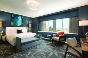 Fairmont The Queen Elizabeth hotel room. Gay-friendly hotel with a bed, chair, desk, and city view. Luxury travel for gay men.
