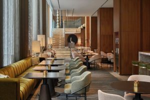 Four Seasons Hotel Toronto at Yorkville interior. Upscale lounge area with tables, chairs, and a staircase. A gay-friendly hotel.