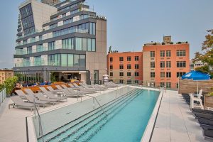 Rooftop pool at Hotel Indigo Williamsburg, Brooklyn. Gay-friendly hotel with lounge chairs, bar, and city views. Perfect for gay men's travel.