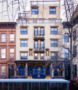 Hotel Scherman, a gay-friendly hotel. Building facade with blue and yellow accents. Balconies, statues, and architectural details.